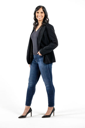 professional woman in sustainable black blouse and blazer with jeans and heels